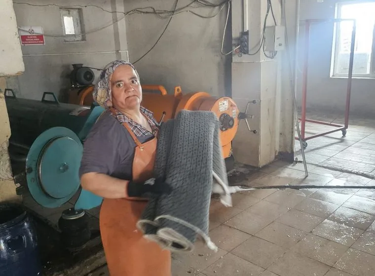 Yıkanan halıyı taşıyan ekip üyesi